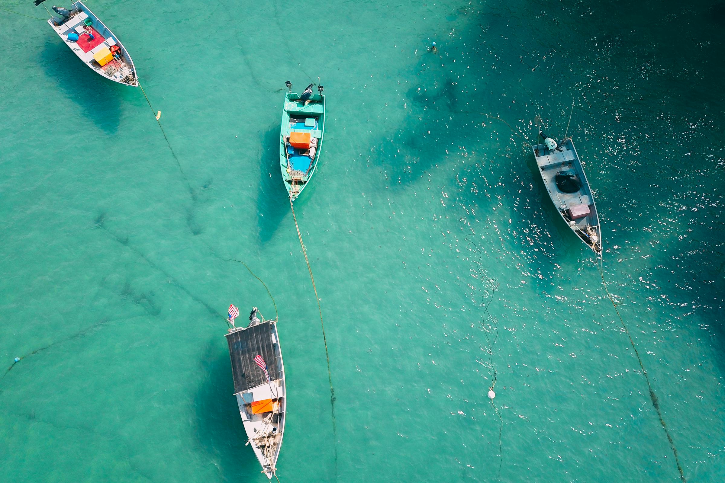 Colourful boats floating on calm crystal-clear turquoise tropical waters